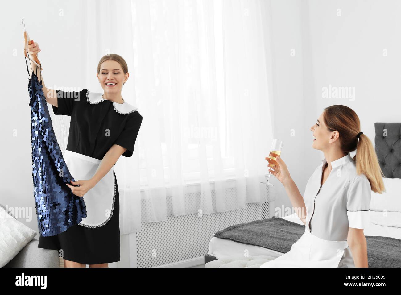 Young chambermaids trying on clothes in hotel room Stock Photo Alamy