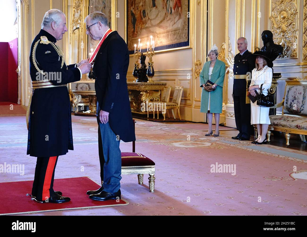 Sir Philip May, the husband of former prime minister Theresa May (watching at right), is knighted for political service by the Prince of Wales during an investiture ceremony at Windsor Castle. Picture date: Wednesday October 20, 2021. Stock Photo