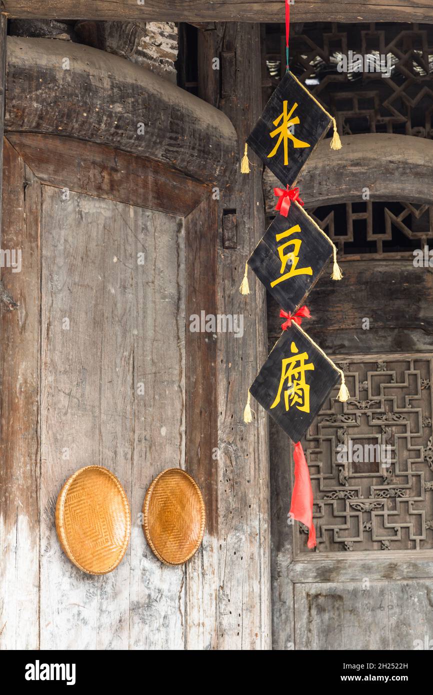 Woven bamboo baskets & a banner with Chinese characters decorate an old building in Furong, China. Stock Photo