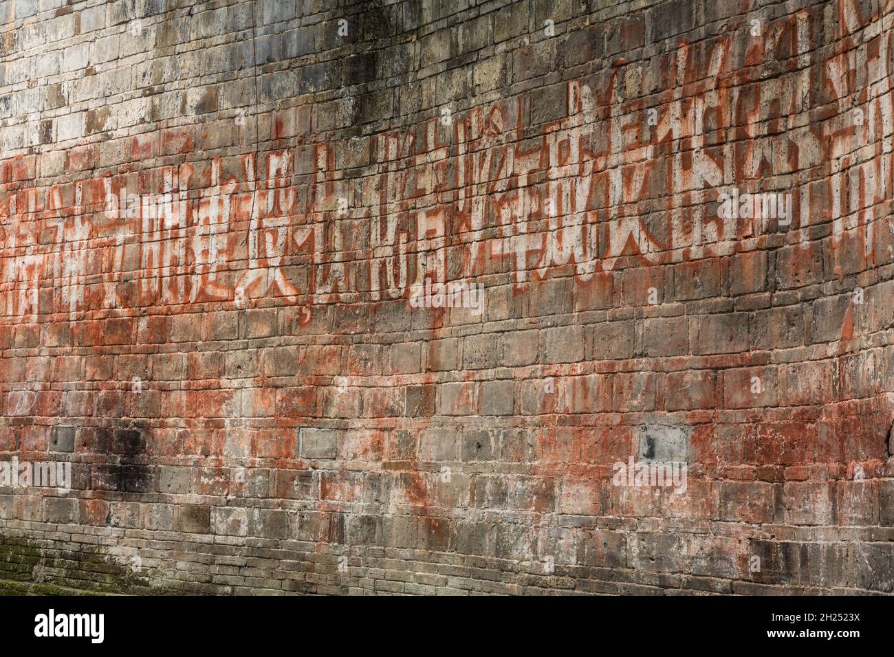 A message in Chinese script wriiten on an old stone wall in the ancient town of Furong, Hunan, China. Stock Photo