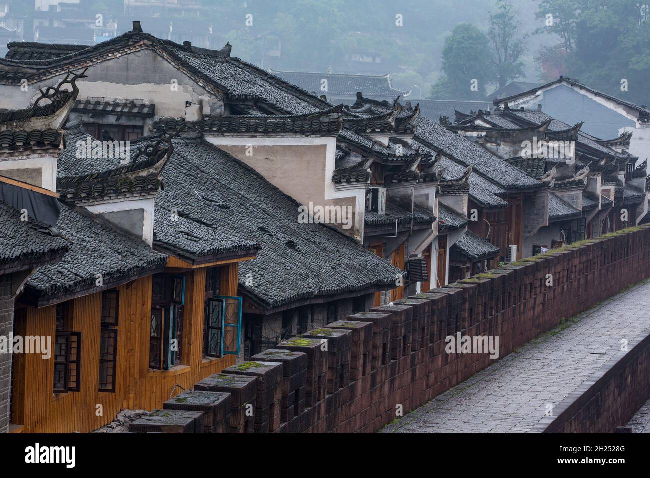 A foggy morning view of the ancient town of Fenghuang from the old city wall.  China. Stock Photo