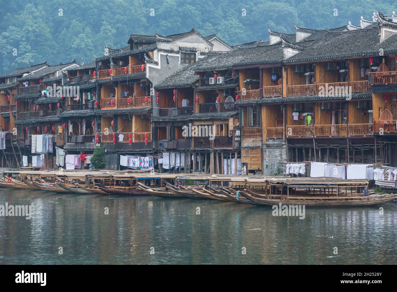 Covered tour boats docked in front Diaojiao-style buildings along the Tuojiang River, Fenghuang, China. Stock Photo