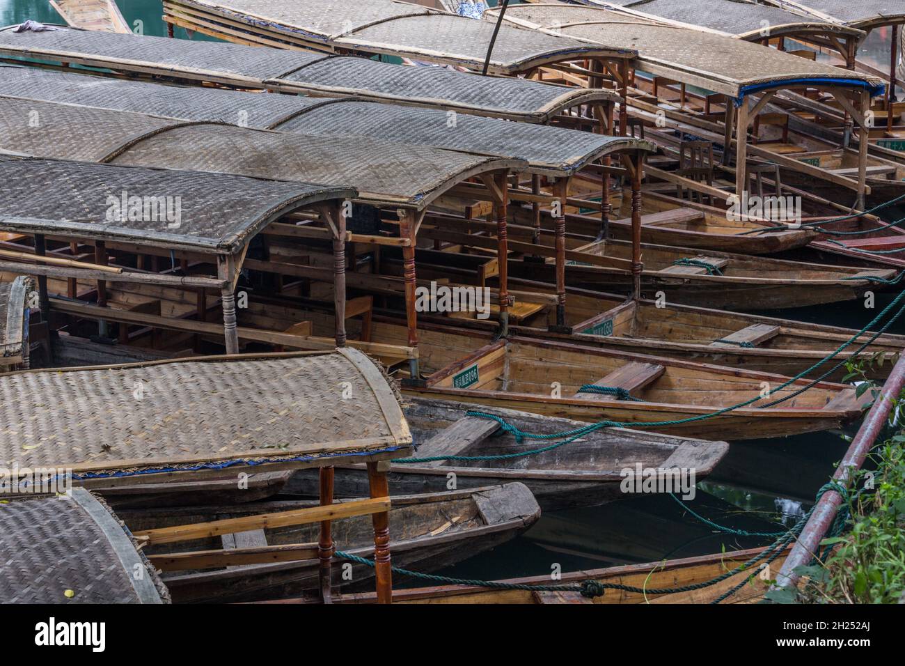 A cluster of covered tour boats tied up on the bank of the Tuojiang River in Fenghuang, China. Stock Photo