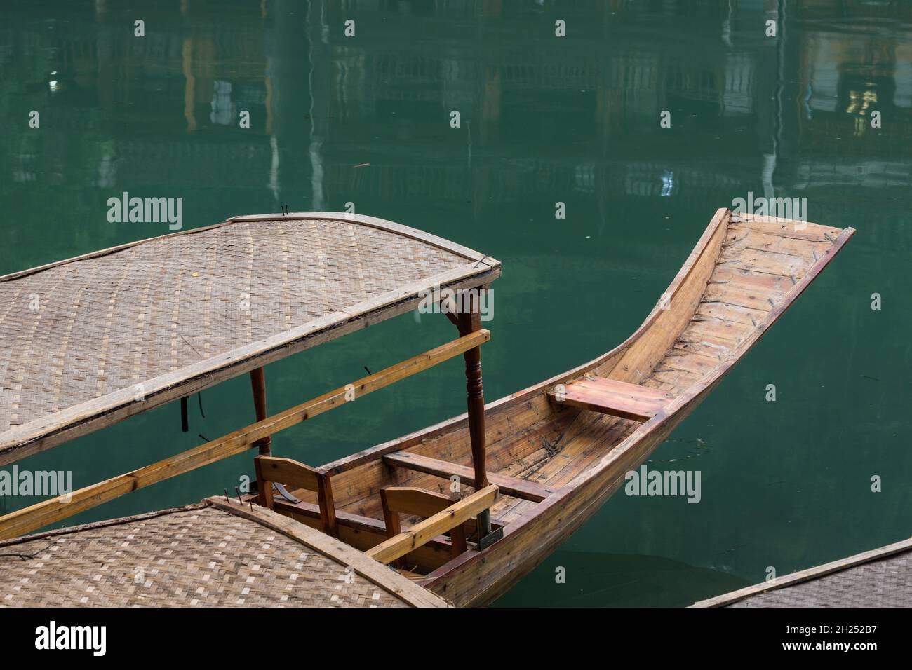A covered tour boat docked on the bank of the Tuojiang River in Fenghuang, China. Stock Photo