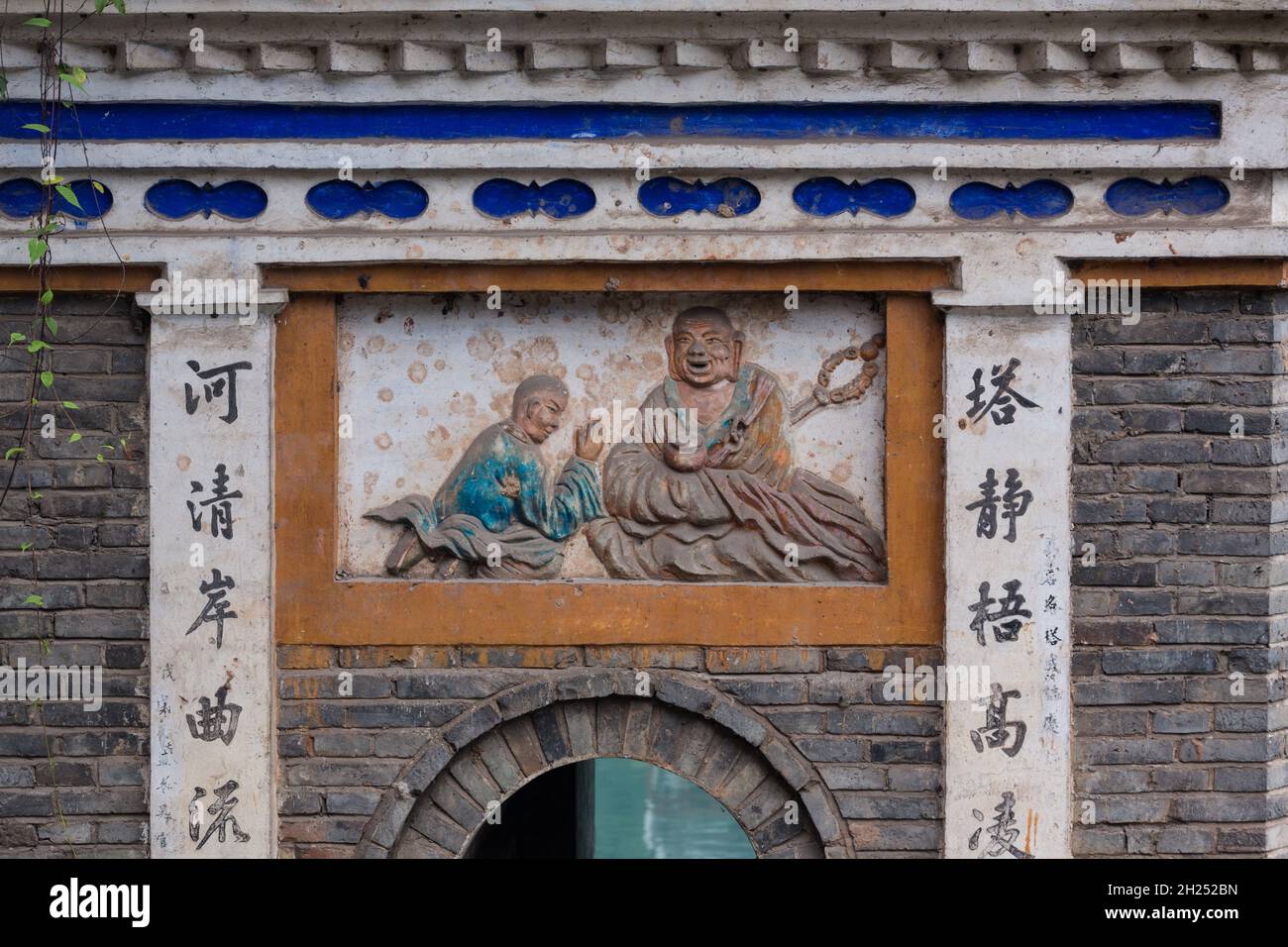 A bas relief frieze of Buddha over a small gate through the city wall of the Fenghuang Ancient Town, China. Stock Photo