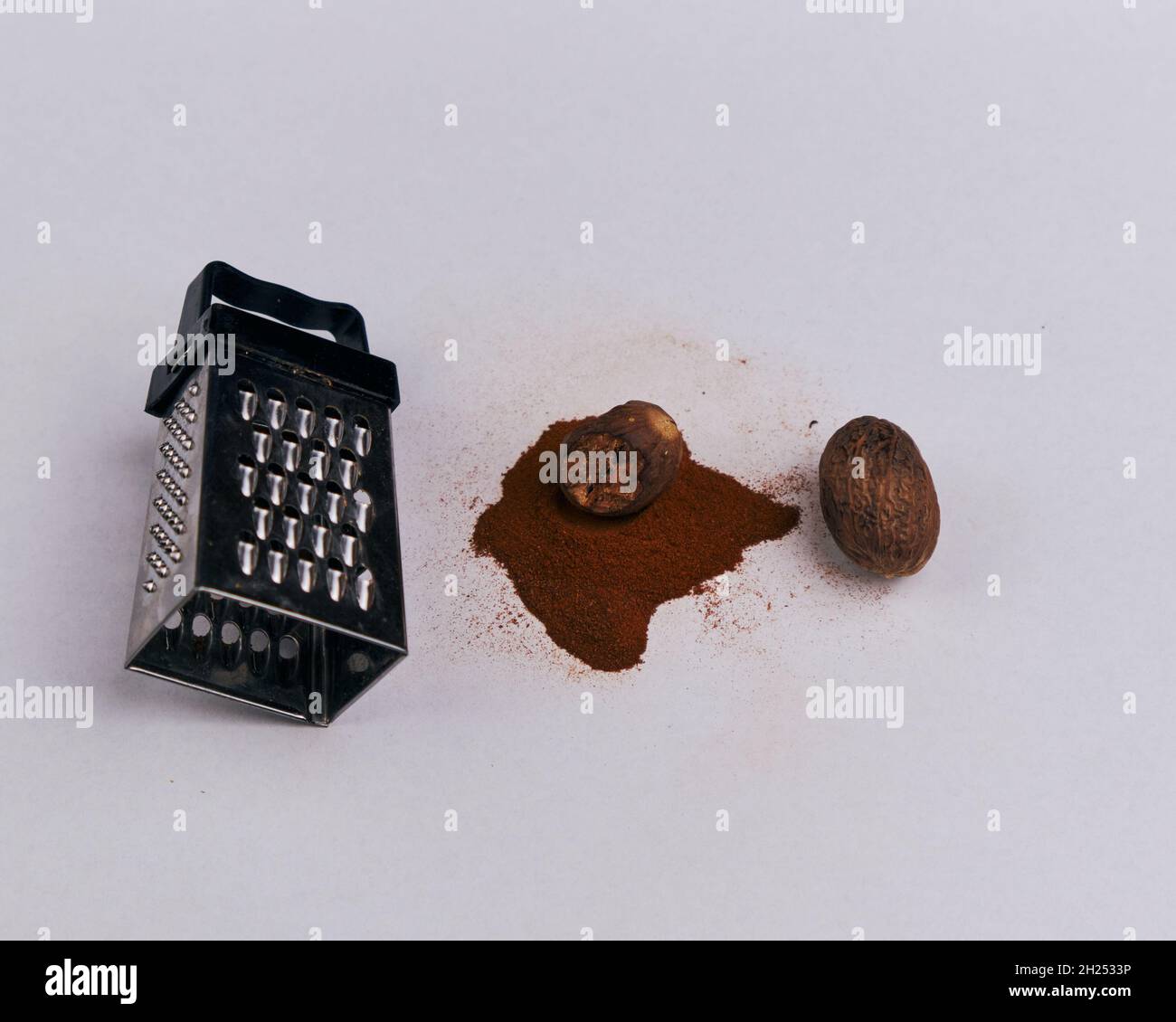 A small grater with nutmeg and powder, isolated on a white background