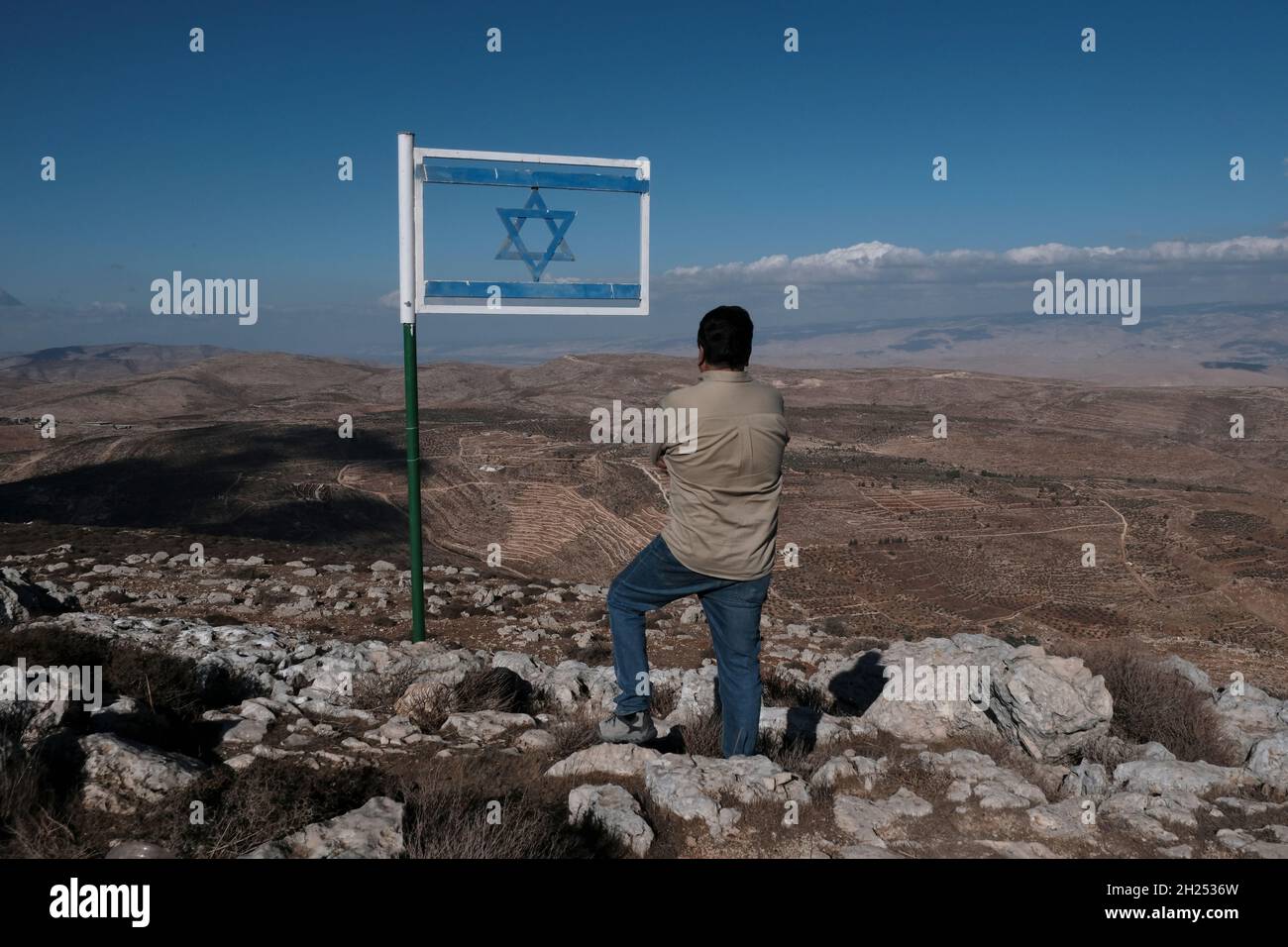 An Israeli civilian stands next to an Israeli flag made from steel placed at Matan Lookout overlooking the hills of Samaria also known as Nablus Mountains located on the Gidonim ridge (a hilltop on which several Jewish settlements are located), above the Israeli settlement of Itamar in the West bank. Israel Stock Photo