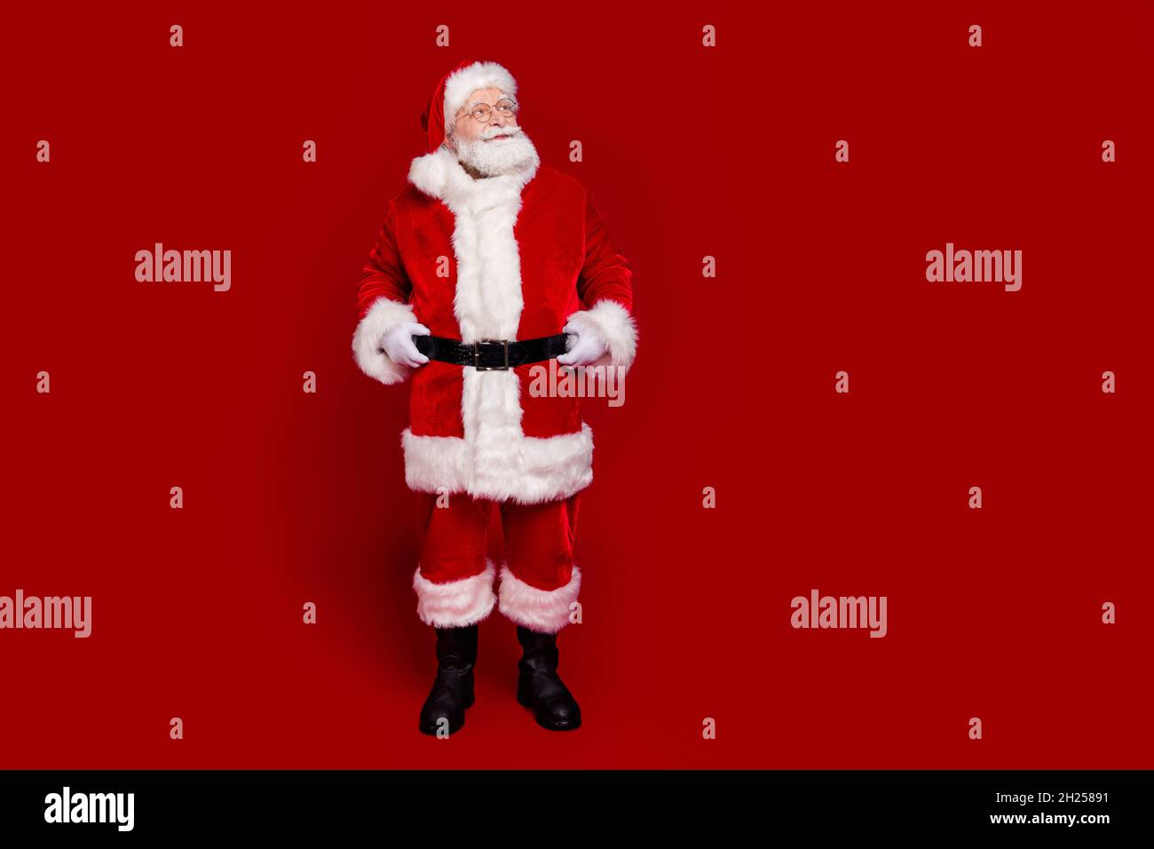 Photo of excited pretty retired man wear santa claus belt boots spectacles walking looking empty space isolated red color background Stock Photo