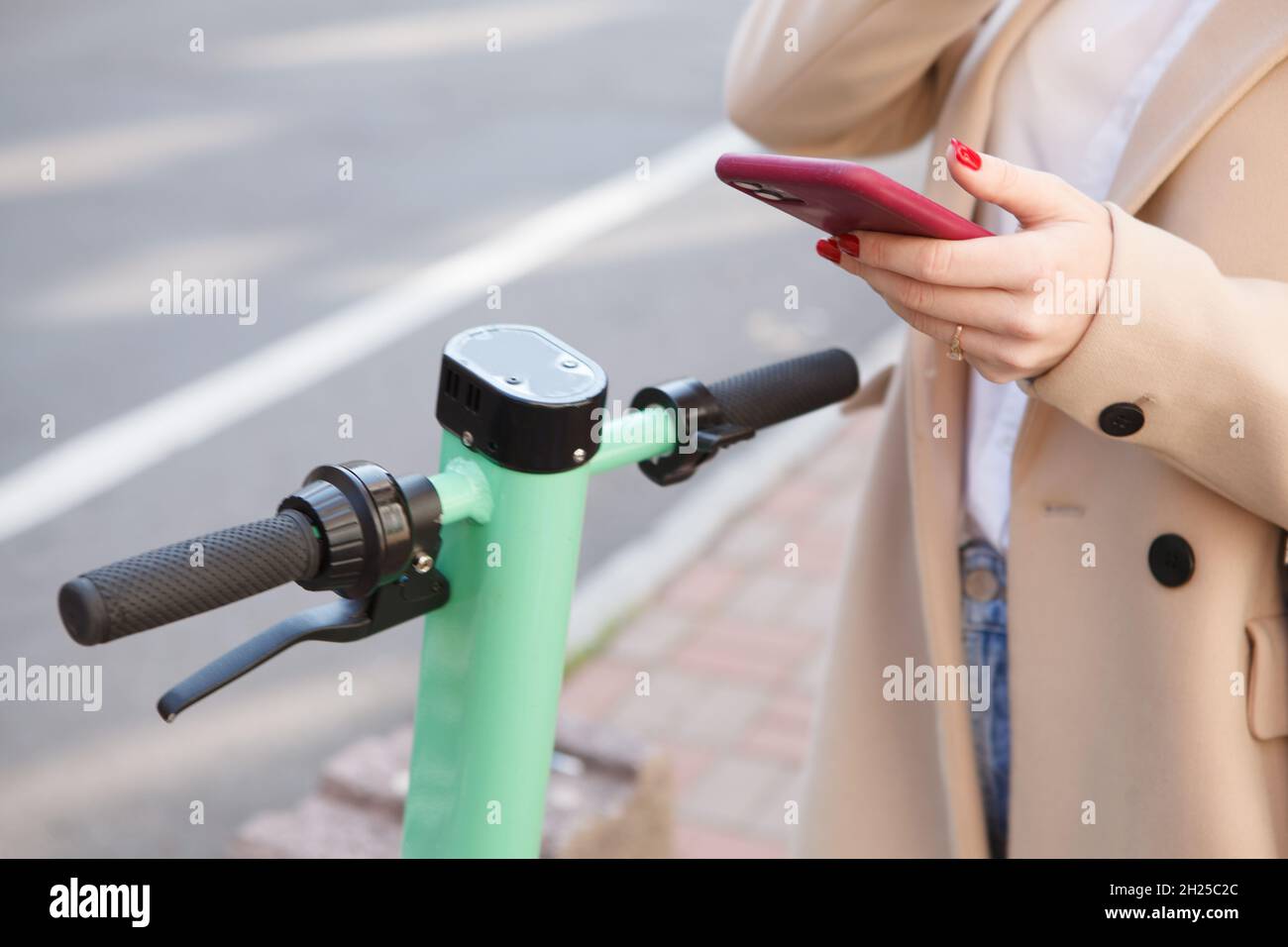 Unrecognizable woman using mobile app on her smart phone to rent electric scooter Stock Photo