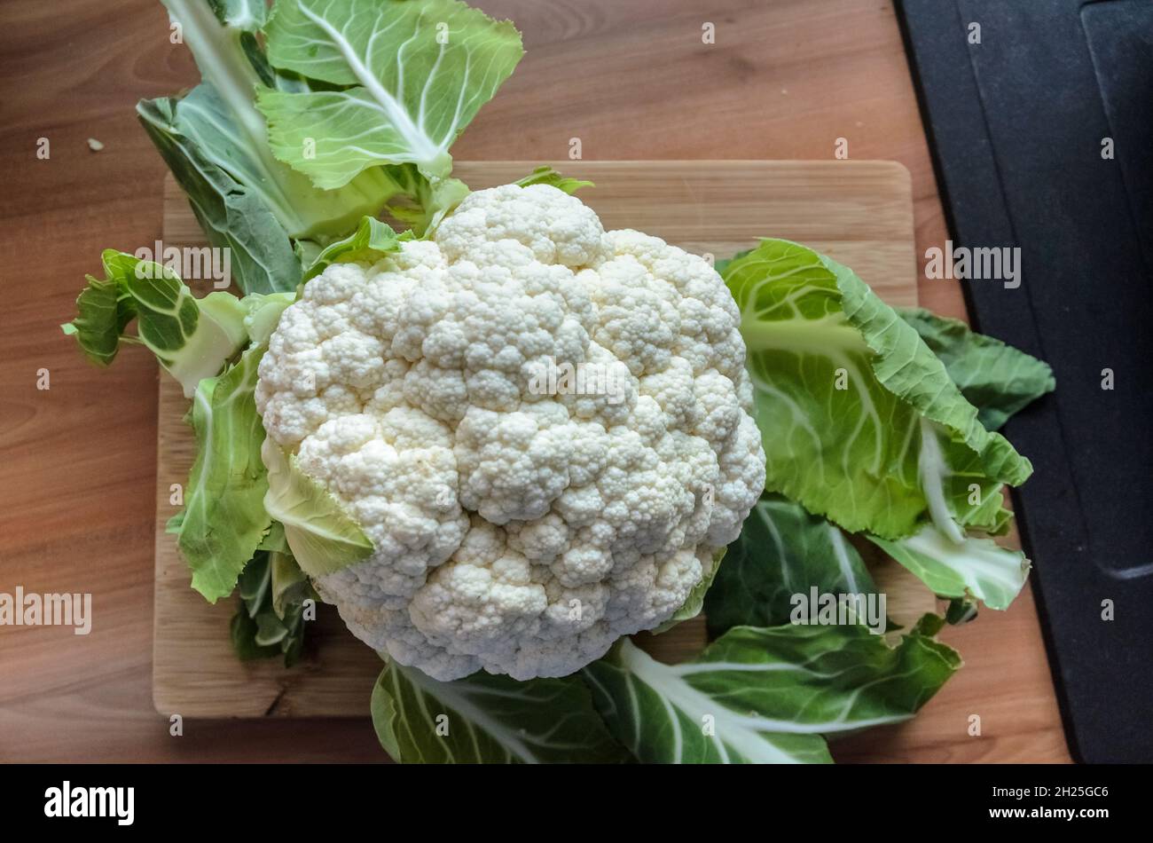 Cauliflower head (Brassica oleracea) with green leaves, close-up view from directly above Stock Photo