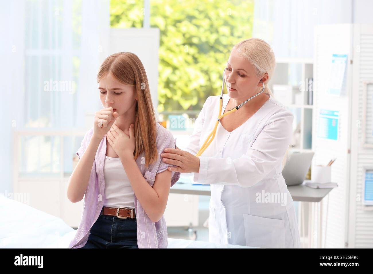 Doctor examining coughing teenage girl at clinic Stock Photo Alamy