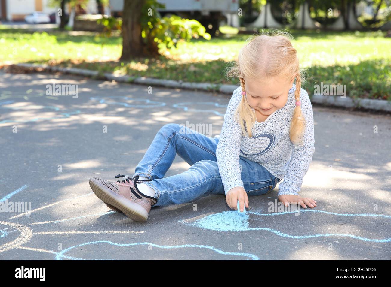 Little child drawing with colorful chalk on asphalt Stock Photo - Alamy