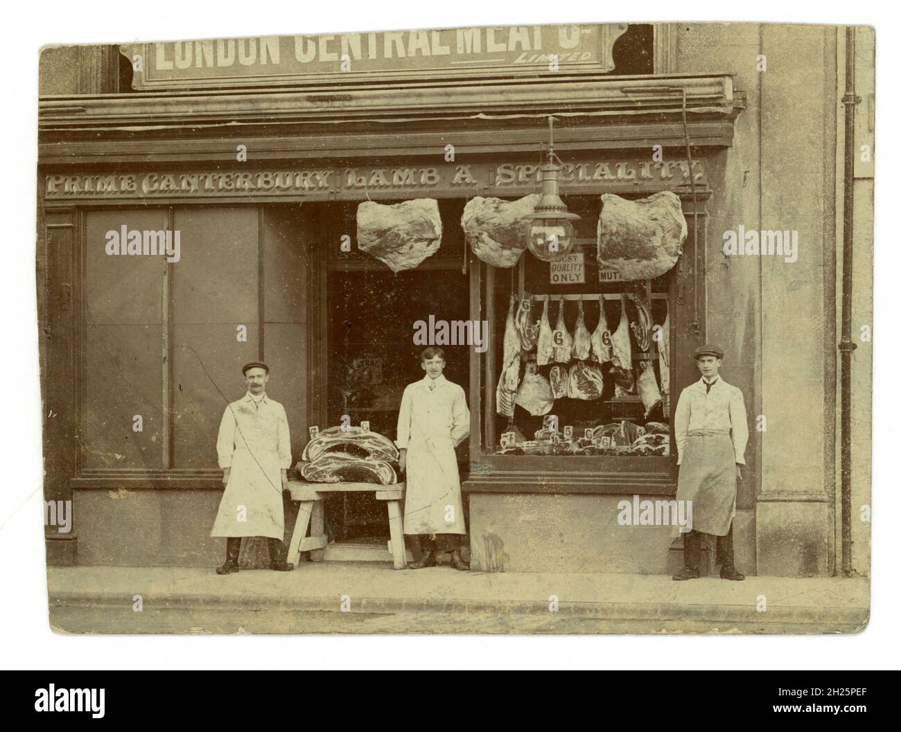 Original Victorian or early Edwardian postcard of the shop front of a butchers shop, huge slabs of meat - beef and lamb on display. Victorian shop. The proprietor or manager stands with his young assistants, apprentices outside, 'London Central Meat Company', 'Canterbury Lamb A Speciality' signs. Photographer: Thomas Bolton, Market Place, Ely, Cambridgeshire, U.K. circa 1901-1904 Stock Photo