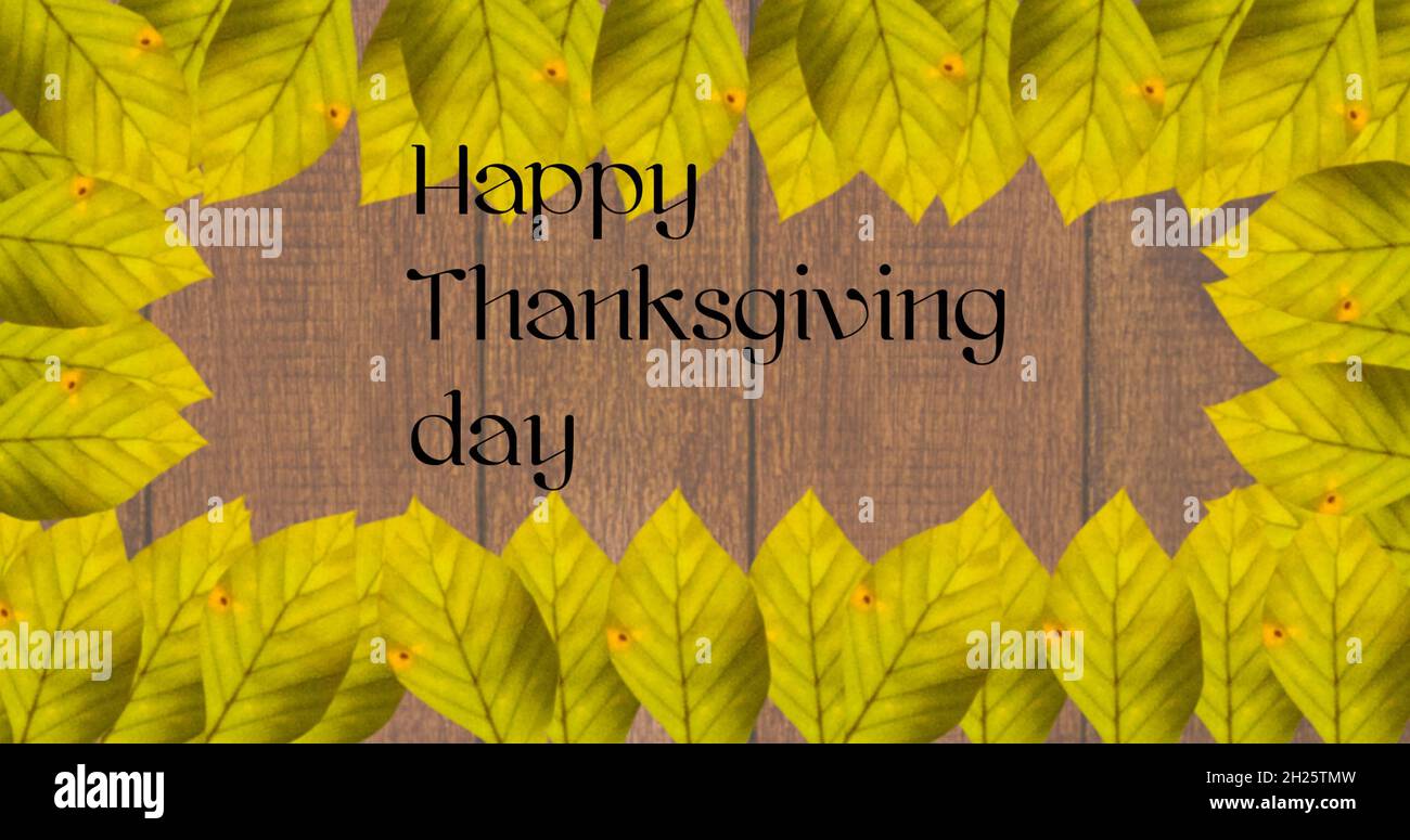 Happy thanksgiving day text and frame of autumn leaves against wooden background Stock Photo