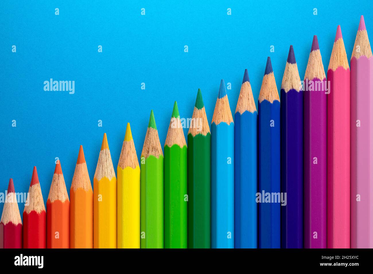 https://c8.alamy.com/comp/2H25XYC/colour-pencils-arranged-diagonally-on-a-blue-paper-background-2H25XYC.jpg