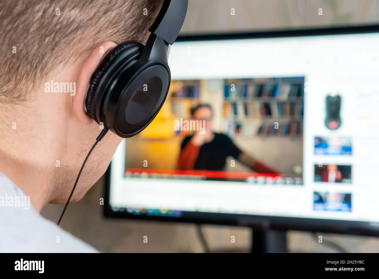 Man Using Computer To Watch Youtube Close-up of a man with headphones watching a video on the Internet on a ...