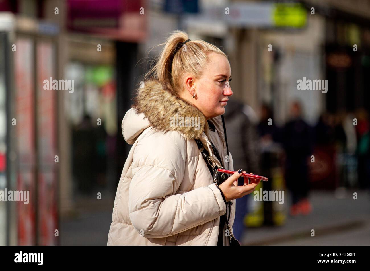 Dundee, Tayside, Scotland, UK. 20th Oct, 2021. UK Weather: A warm sunny Autumn day with a strong breeze across North East Scotland, temperatures reaching 14°C. An attractive young woman is spending the day out enjoying the October sunshine talking on her mobile phone whilst shopping in Dundee city centre. Credit: Dundee Photographics/Alamy Live News Stock Photo