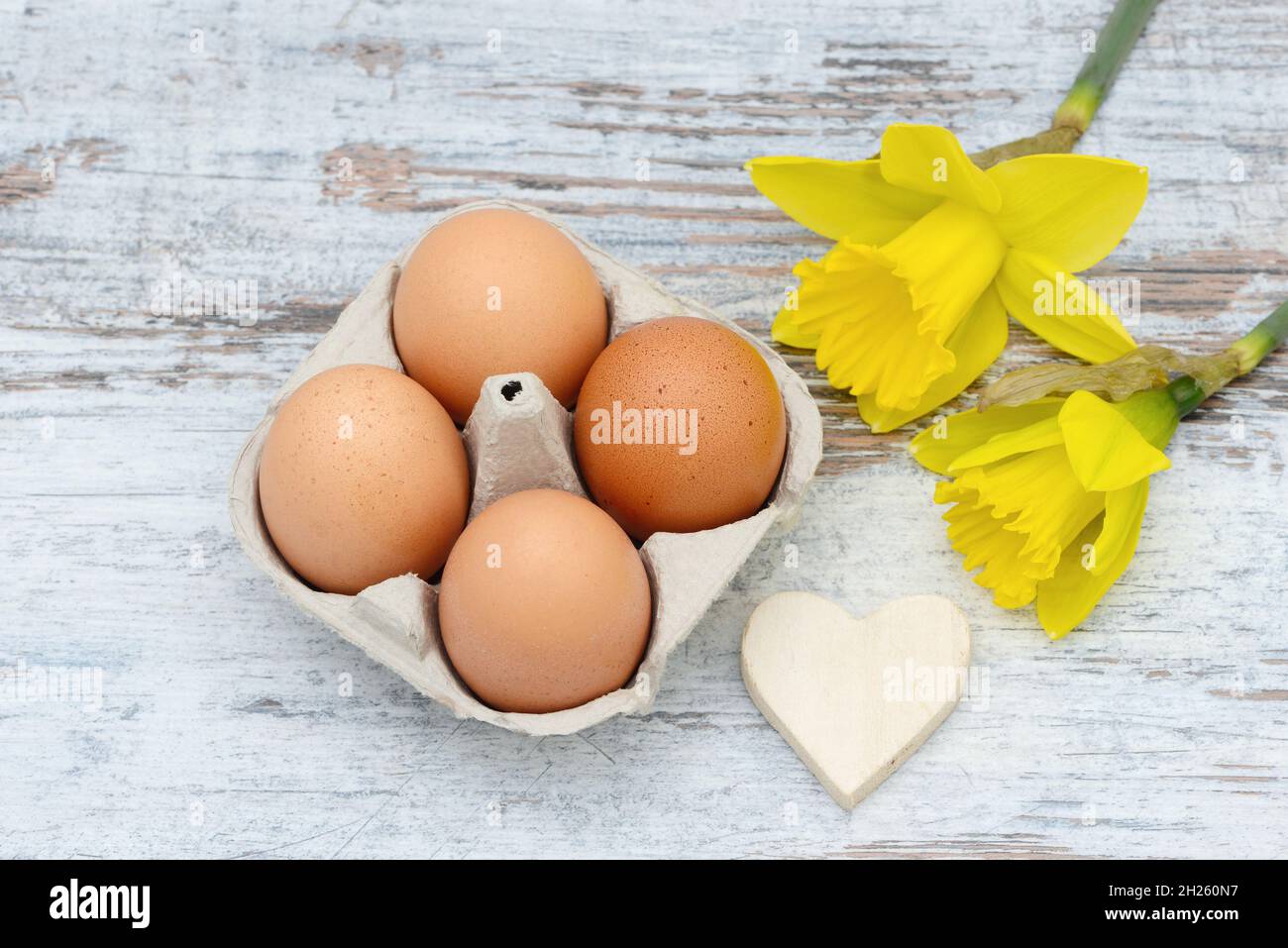 Easter eggs, Heart and daffodil lying on wood Stock Photo