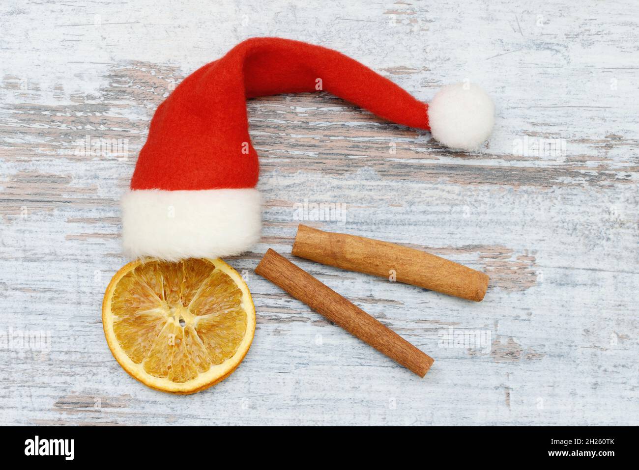 orange slices and cinnamon stick with santa hat on wood Stock Photo