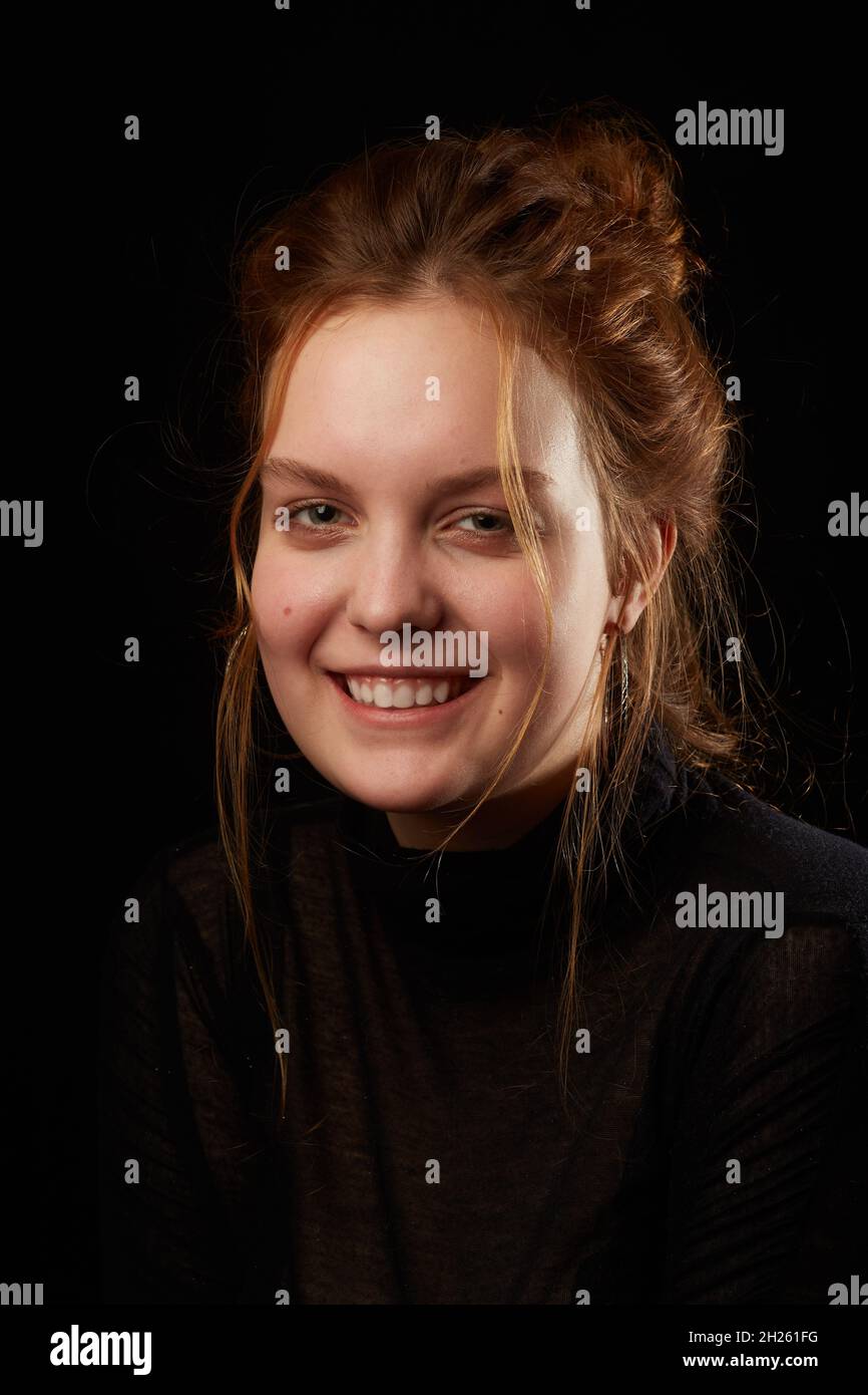 serious sad young woman with down syndrome on black background looking at camera smiling Stock Photo