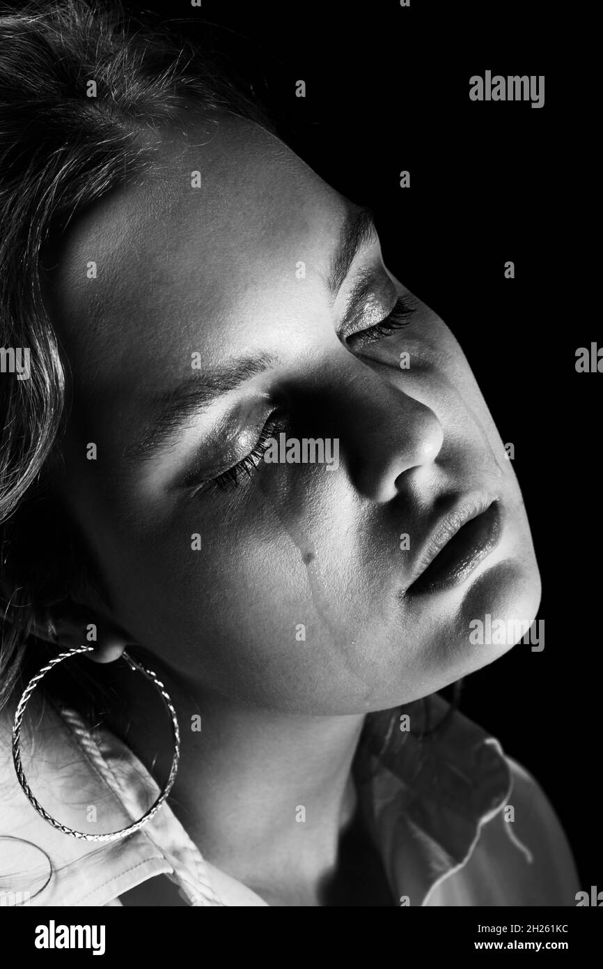 sad woman with closed eyes crying, on black background, closeup portrait, closeup view, monochrome Stock Photo