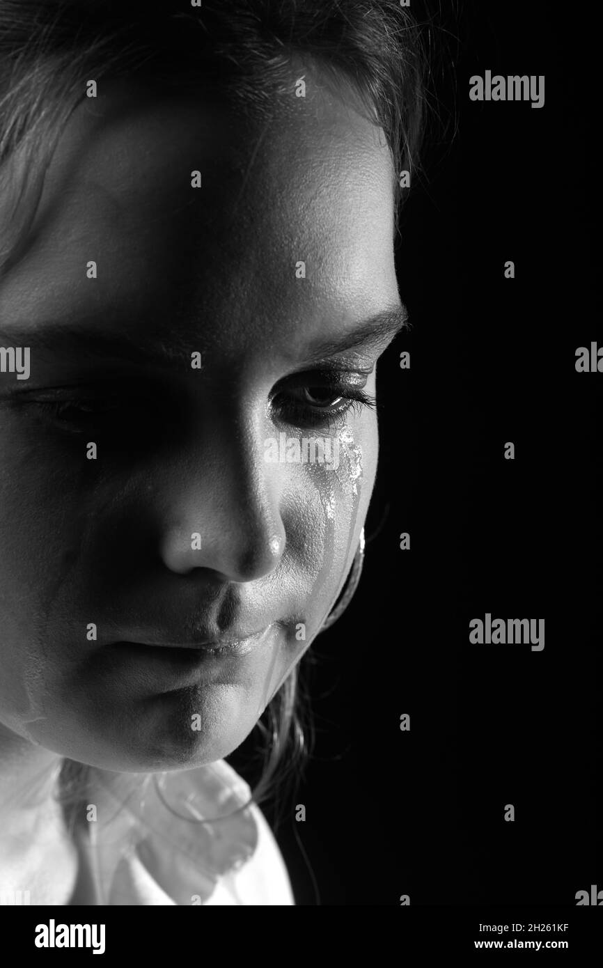 sad woman crying, looking aside on black background, closeup portrait, monochrome Stock Photo