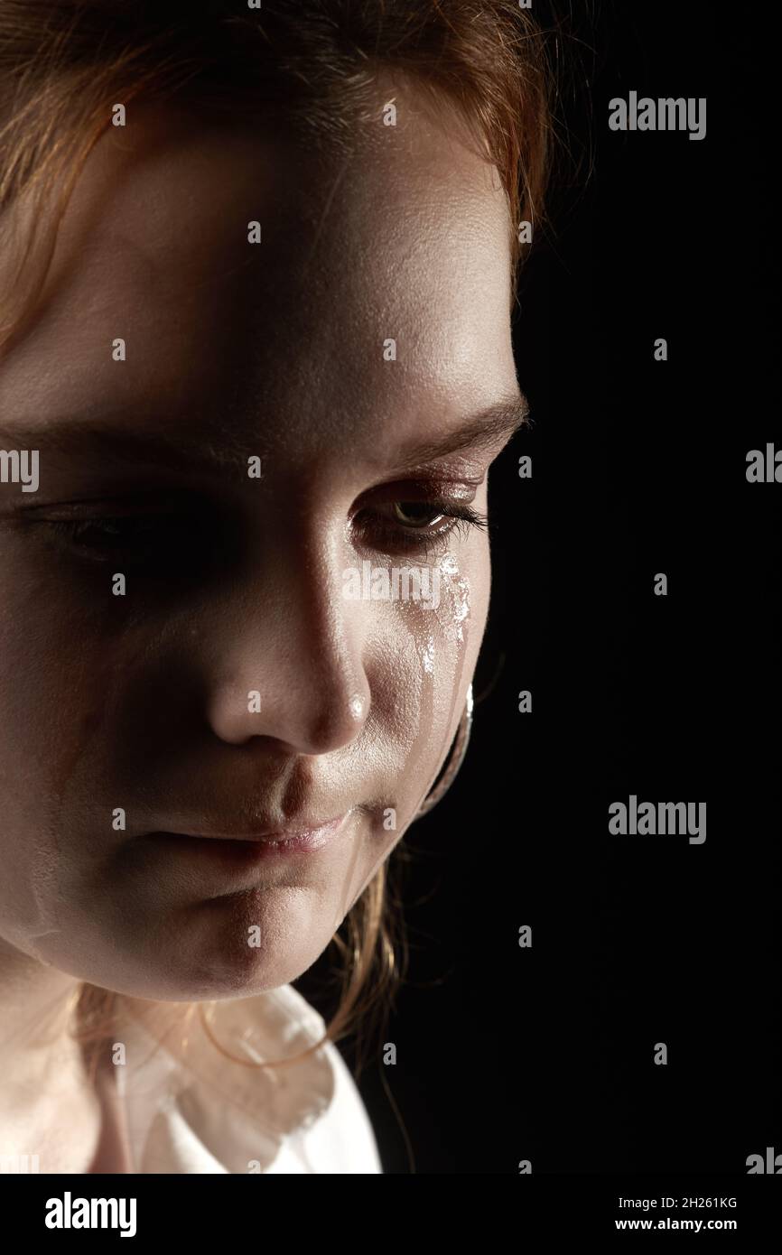 sad woman crying, looking aside on black background, closeup portrait ...