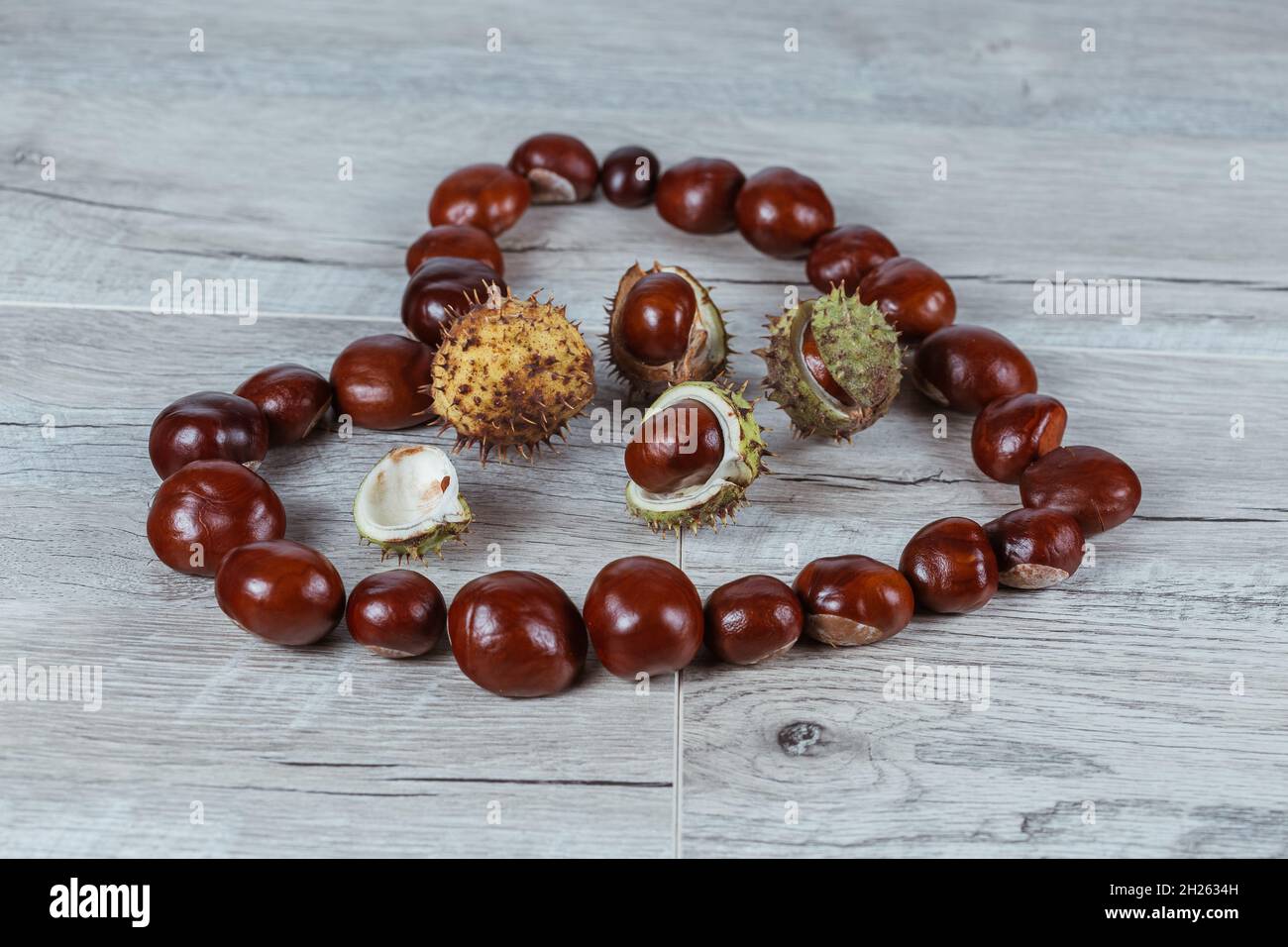 Chestnuts in a heart shape on a wooden background. Stock Photo