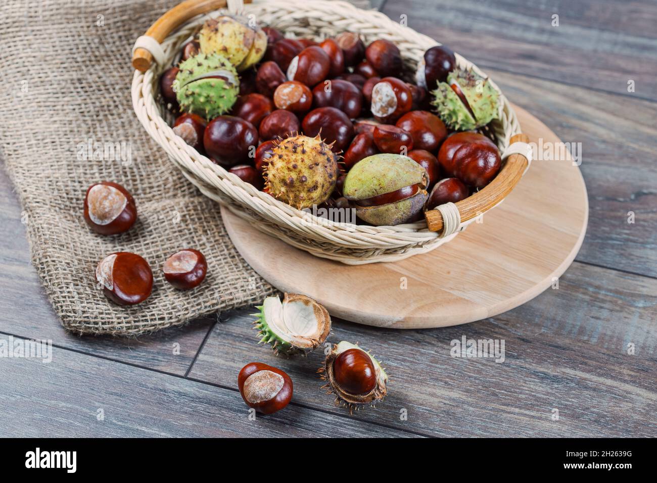 Close up view of Chestnuts in a basket on a wooden background. Stock Photo