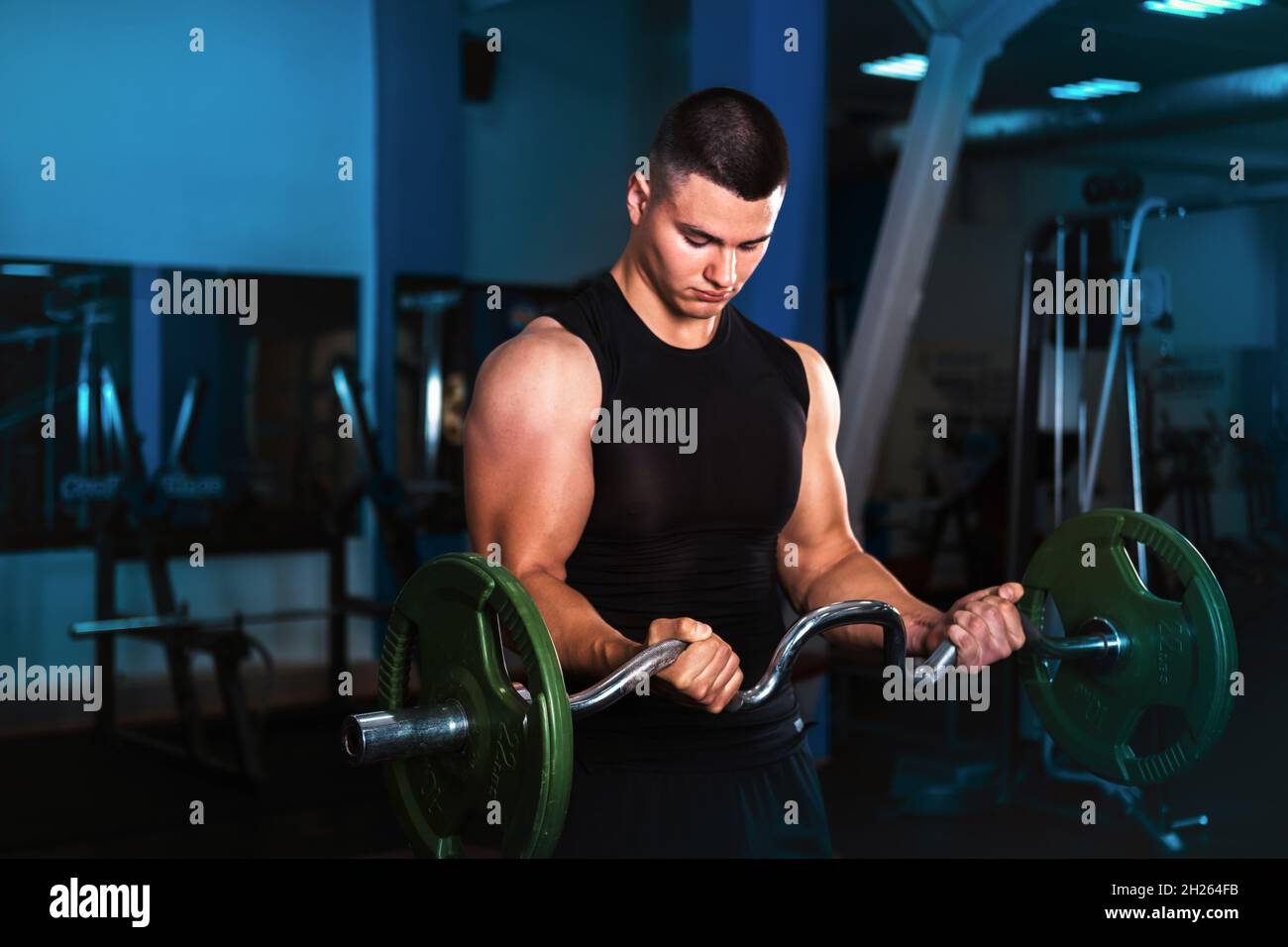 A young athlete does exercises for biceps a barbell with a curved bar Stock Photo Alamy