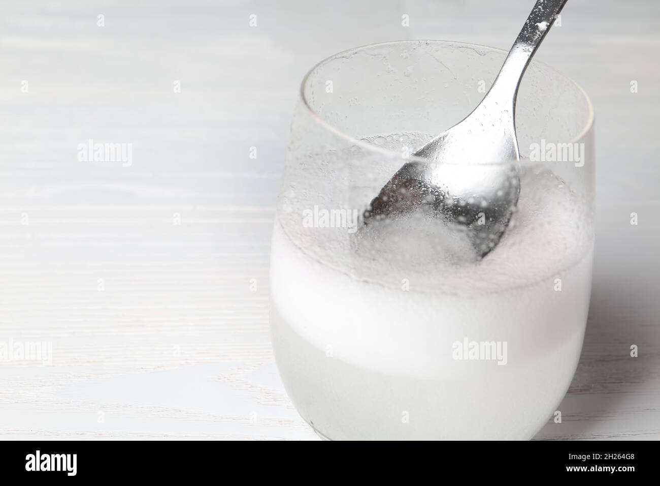 Chemical reaction of vinegar and baking soda in glass on table. Space