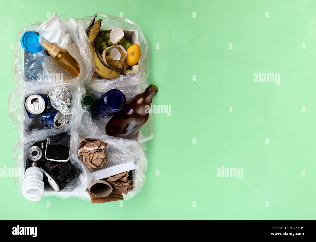 Top view photo of segregated waste materials laid on green isolated background. waste management concept Stock Photo