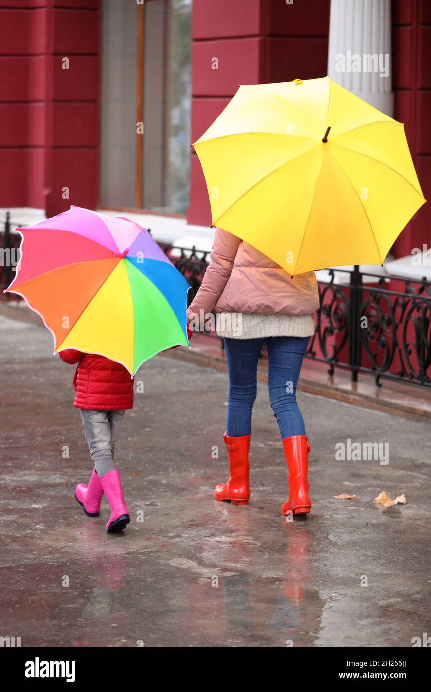 Mother and daughter with umbrellas taking autumn walk in city on rainy ...