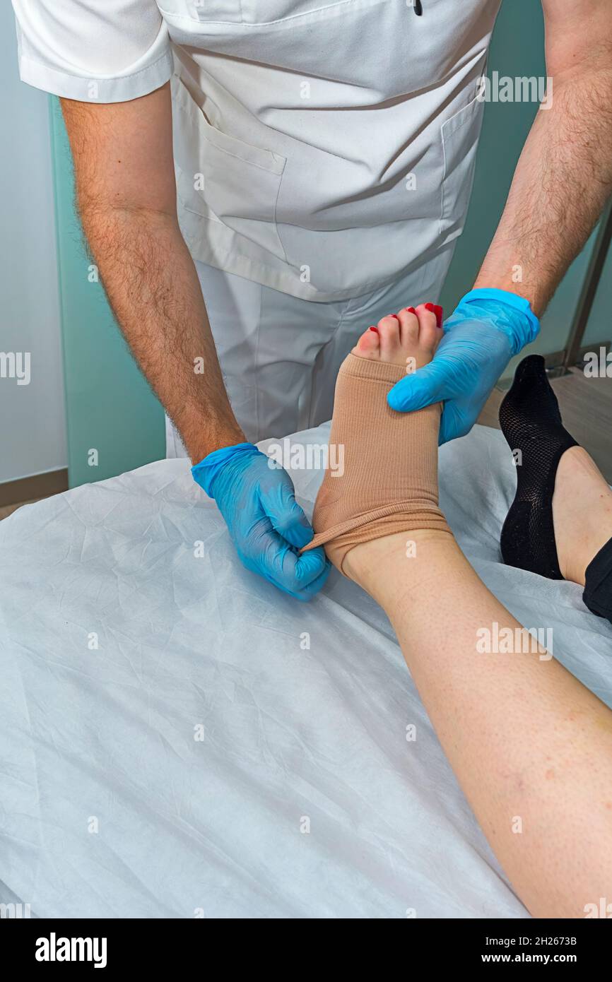 Physician working on examining a girl's injured foot Stock Photo