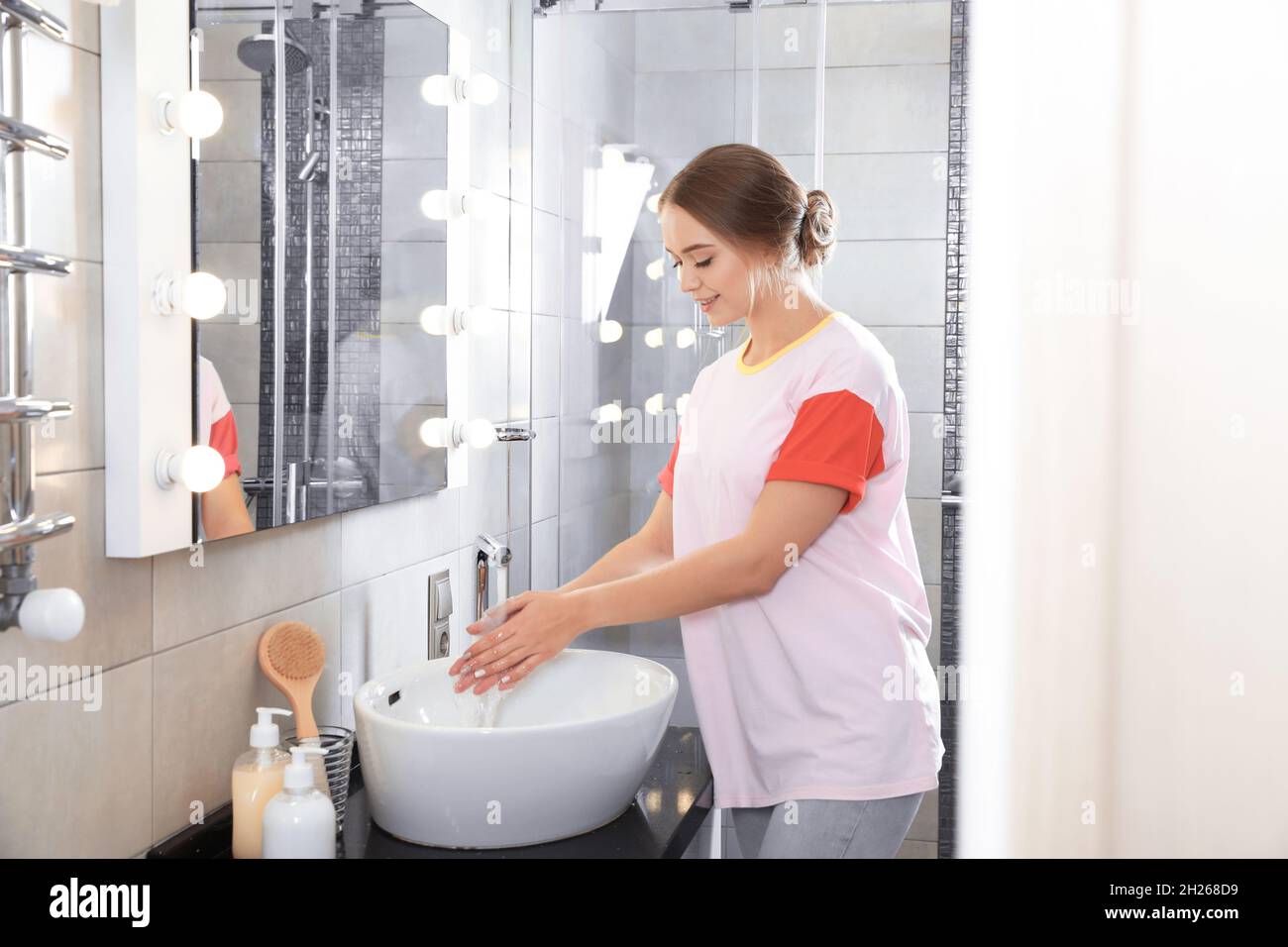 Young woman washing hands in bathroom. Using soap Stock Photo - Alamy