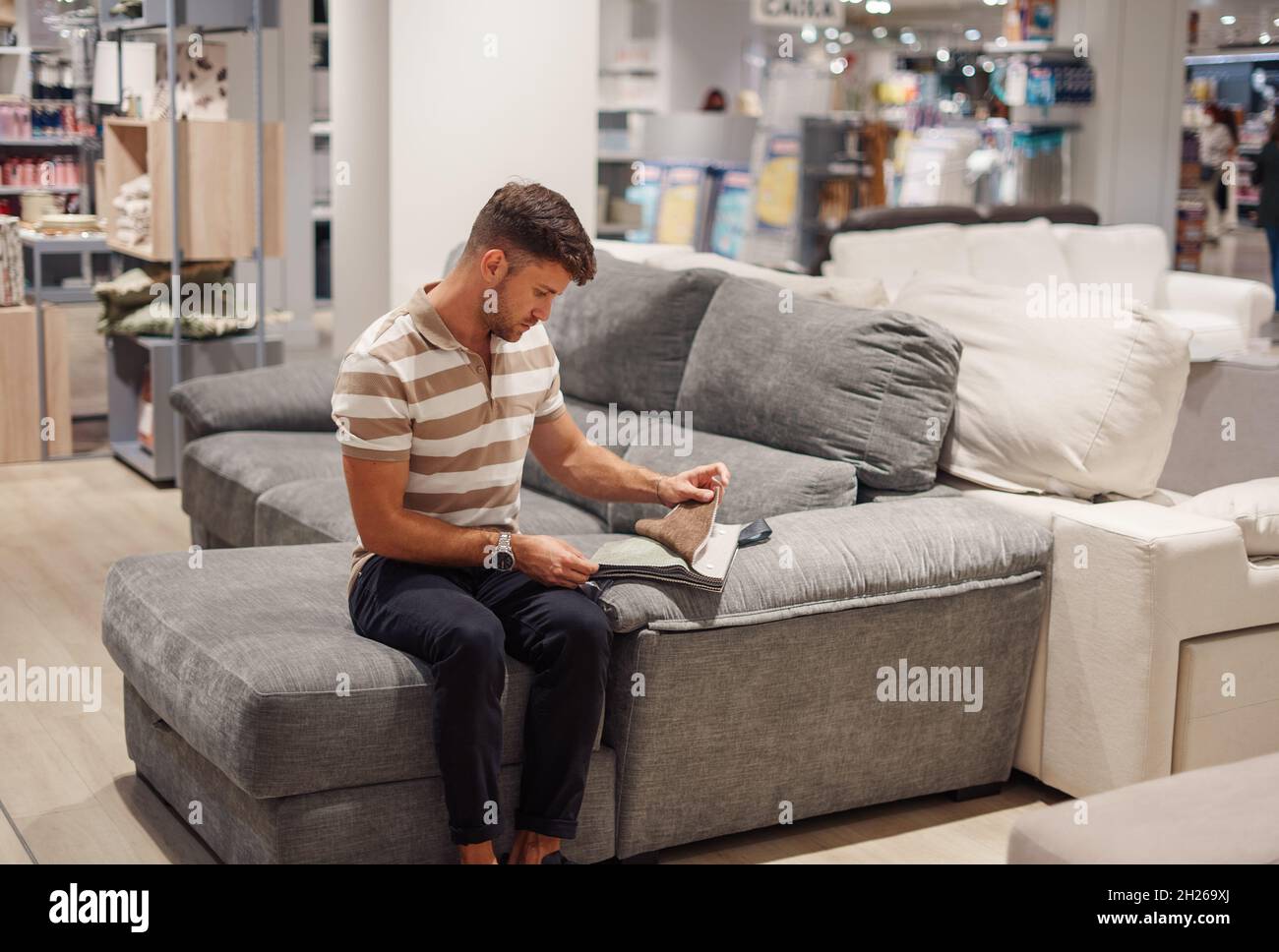 Male customer sitting on couch and selecting fabric for upholstery