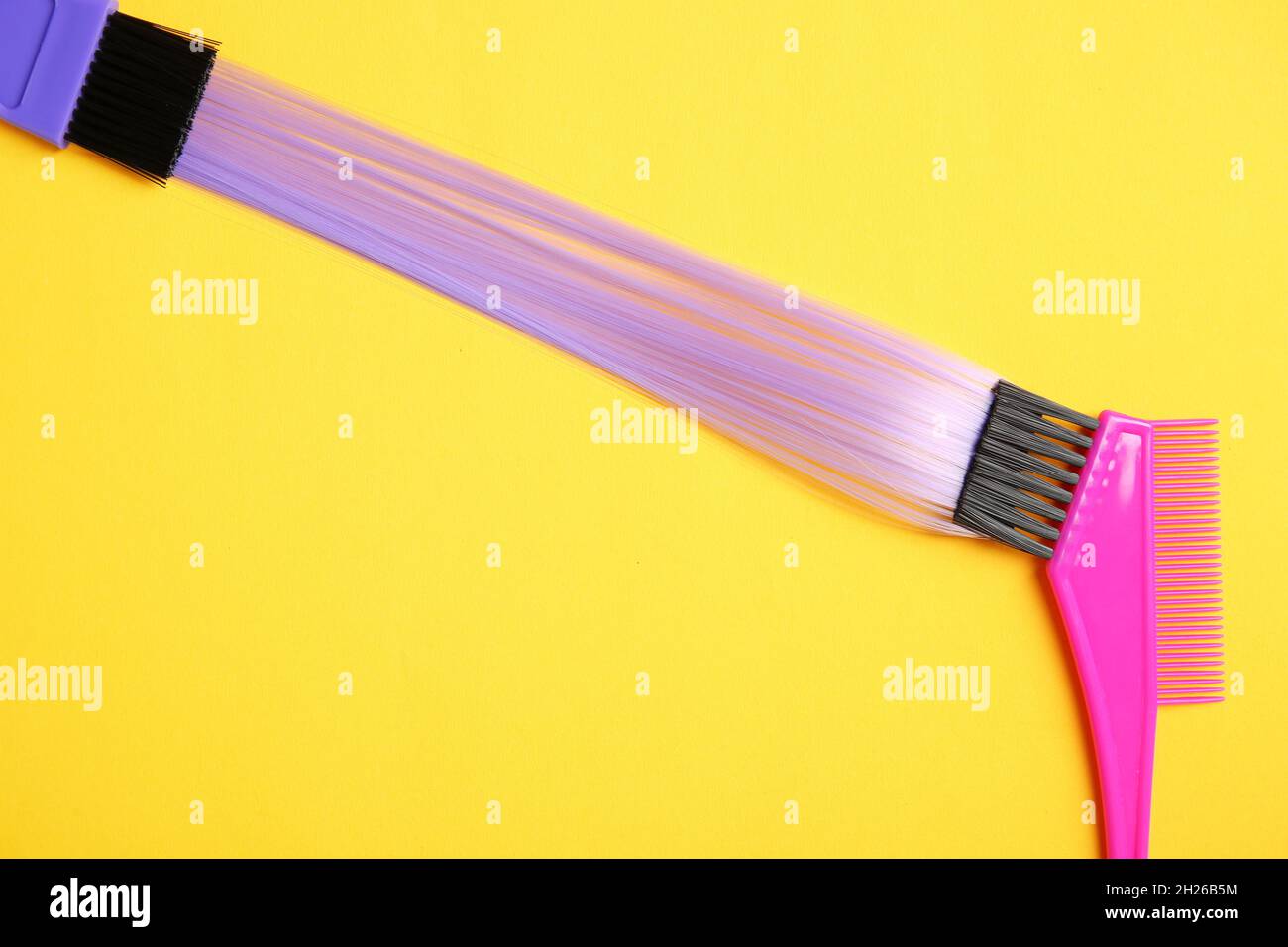 Flat lay composition with strand of hair and brushes on color