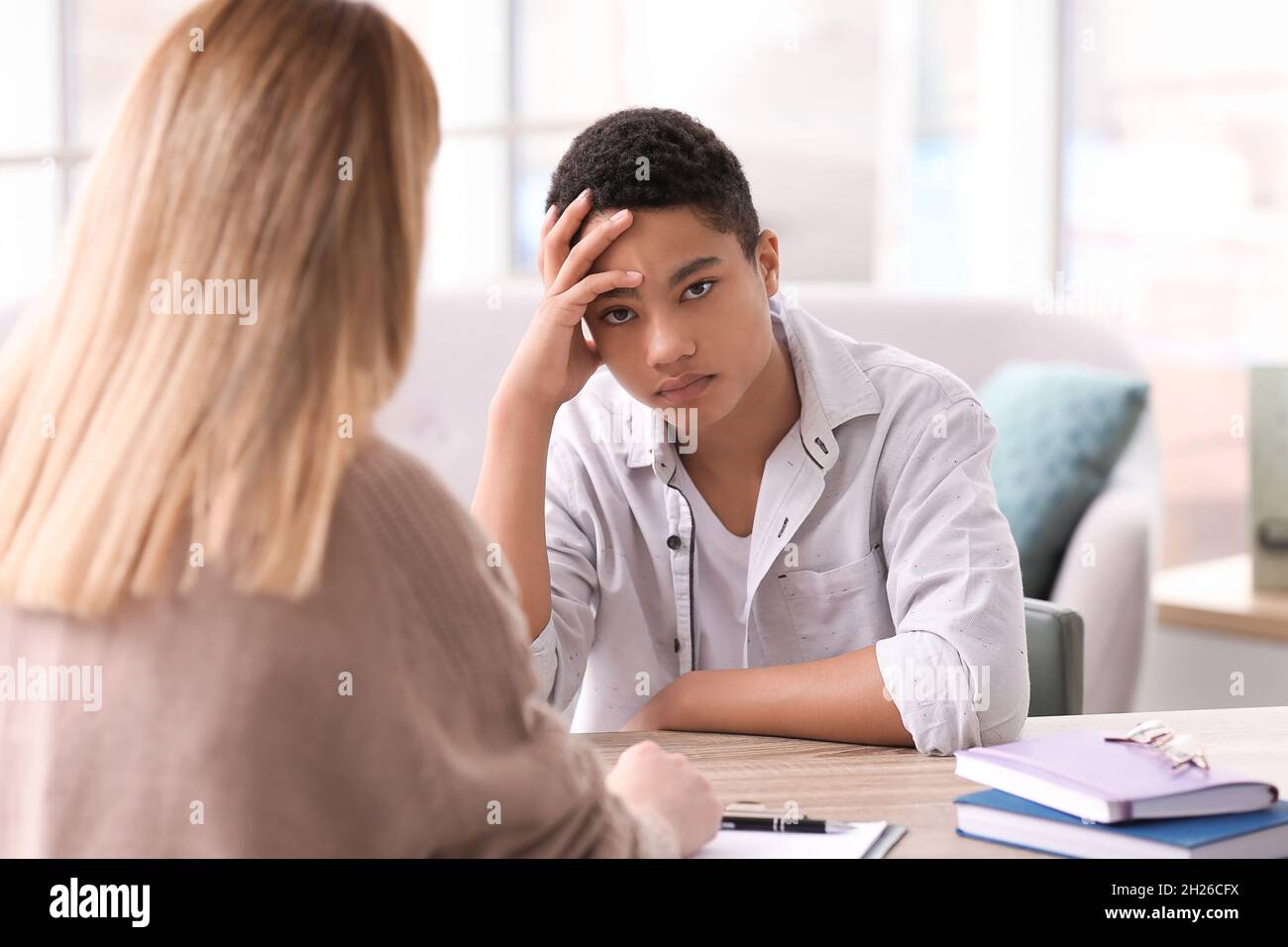 Young female psychologist working with teenage boy in office Stock