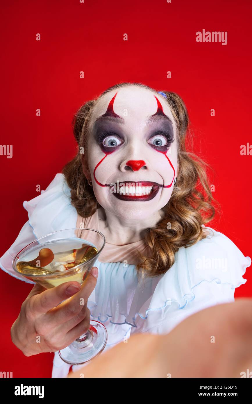 Halloween spooky theme. Close-up beautiful artistic girl in halloween make up looking at camera isolated over red background Stock Photo
