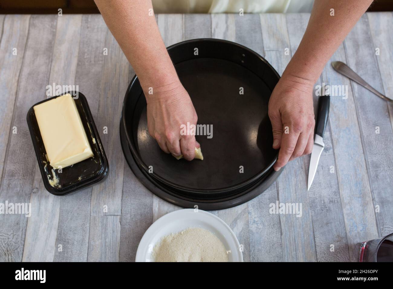 A step-by-step process for making a sour cream chocolate cake. Women's hands prepare a baking dish, grease with butter and sprinkle with semolina. Bak Stock Photo