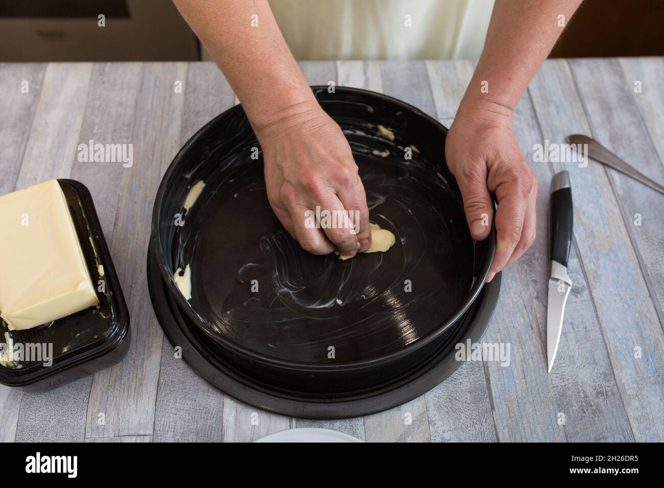 A step-by-step process for making a sour cream chocolate cake. Women's hands prepare a baking dish, grease with butter and sprinkle with semolina. Bak Stock Photo