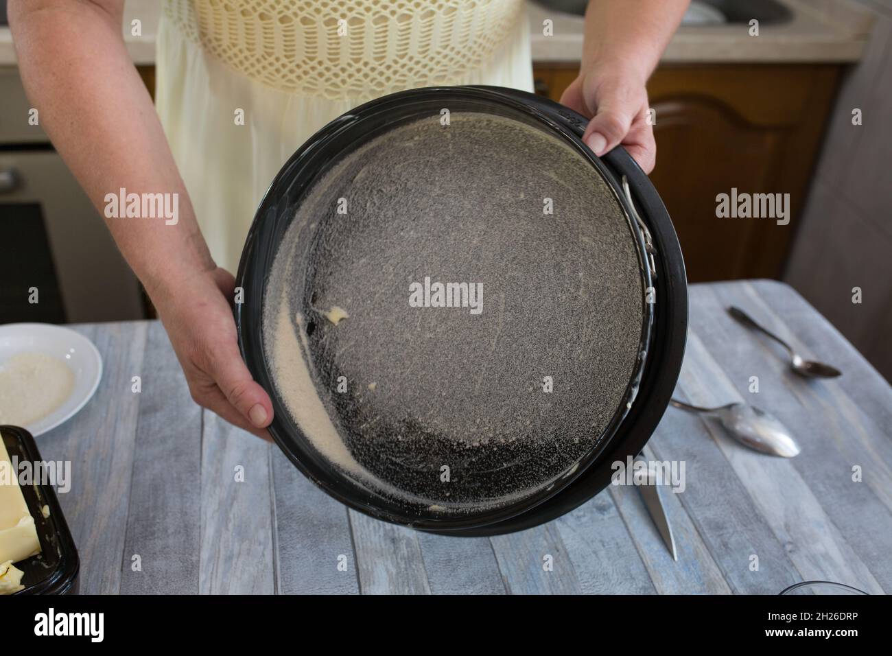 A step-by-step process for making a sour cream chocolate cake. Women's hands prepare a baking dish, grease with butter and sprinkle with semolina. Bak Stock Photo