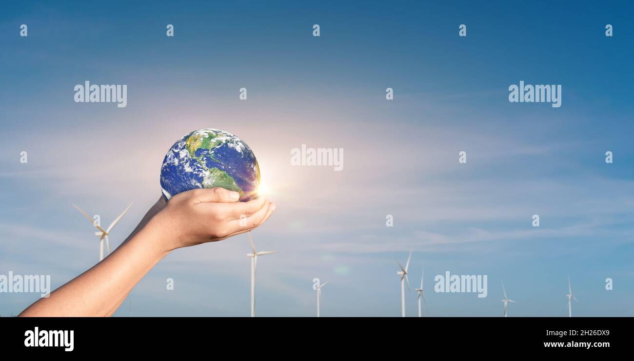 Hands holding Globe, Earth on wind turbine field background. Concept of