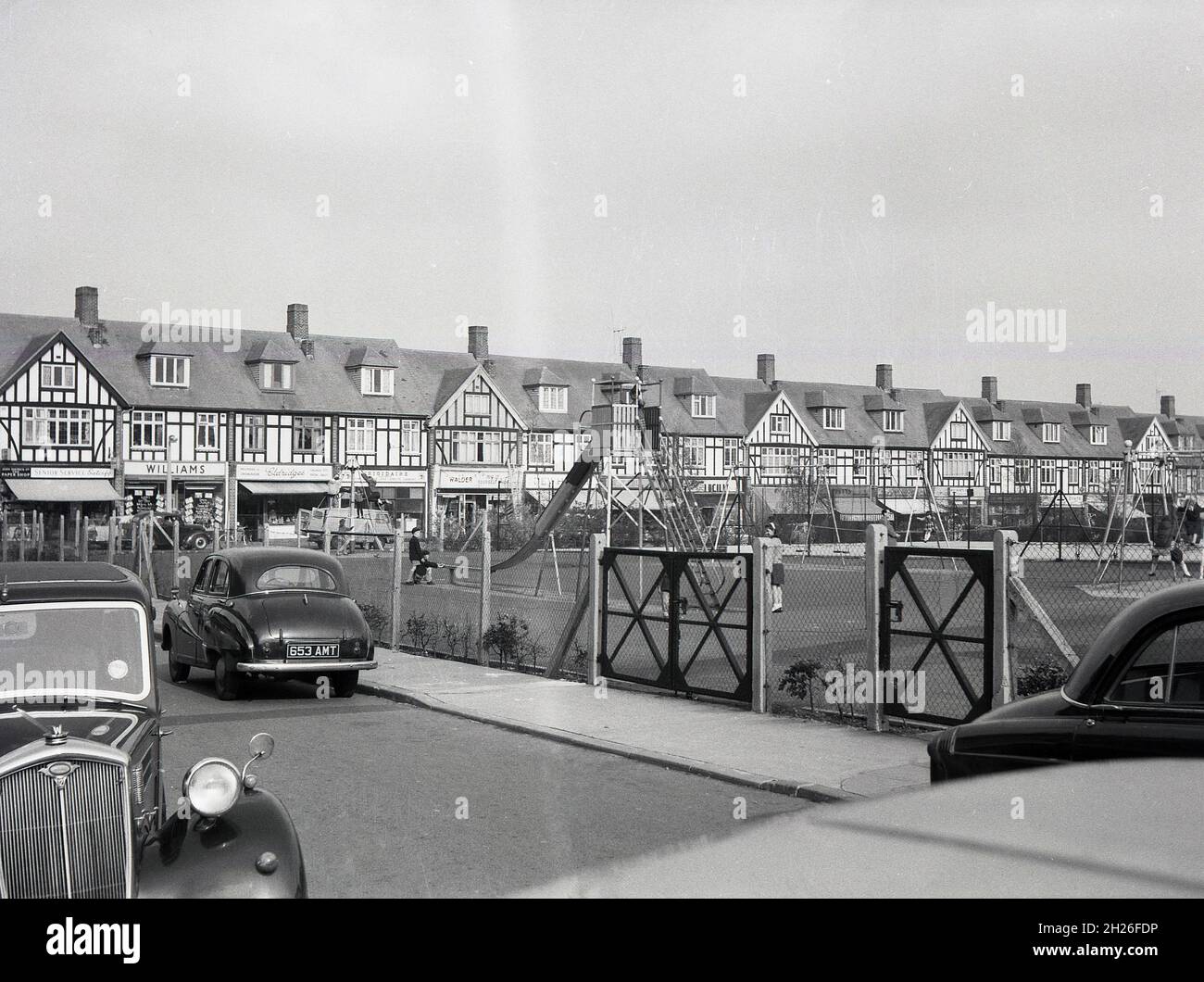 1950s, historical, parade of shops and playground, South east London, England, UK, with cars of the era parked beside. Maybe Abbey Wood or Eltham. Stock Photo