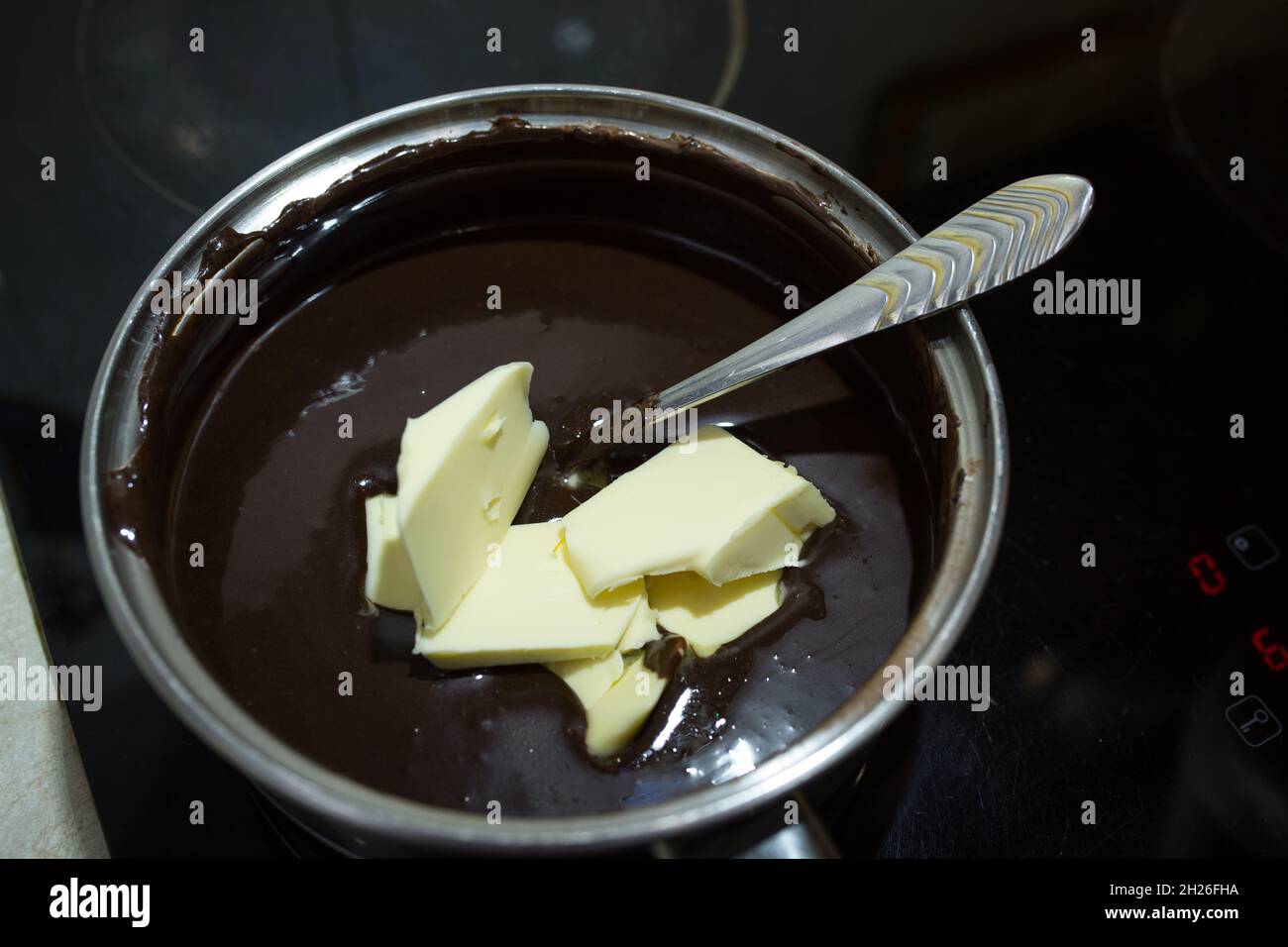 Step-by-step process for making a sour cream chocolate cake. The process of making chocolate glaze. Butter is added to the heated mixture of sour crea Stock Photo