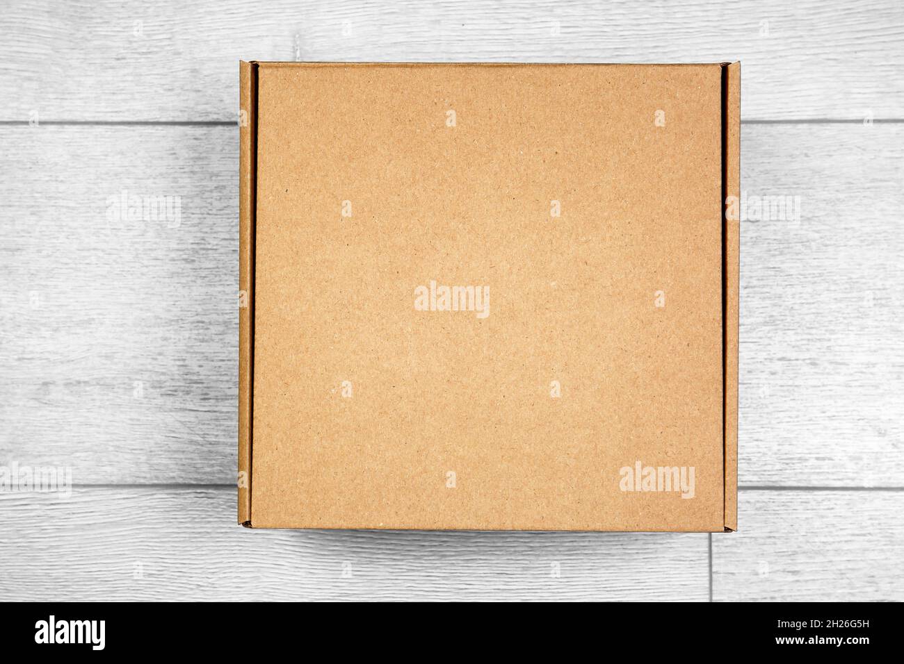 Closed cardboard box on wooden floor Stock Photo - Alamy