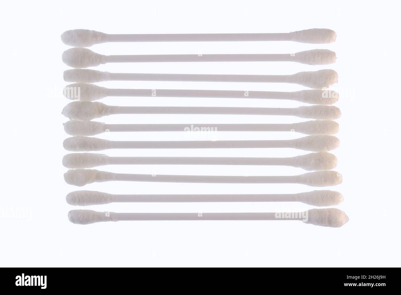 Several white cotton buds with plastic material lined up and isolated on a white background, the concept of health, beauty, and hygiene Stock Photo