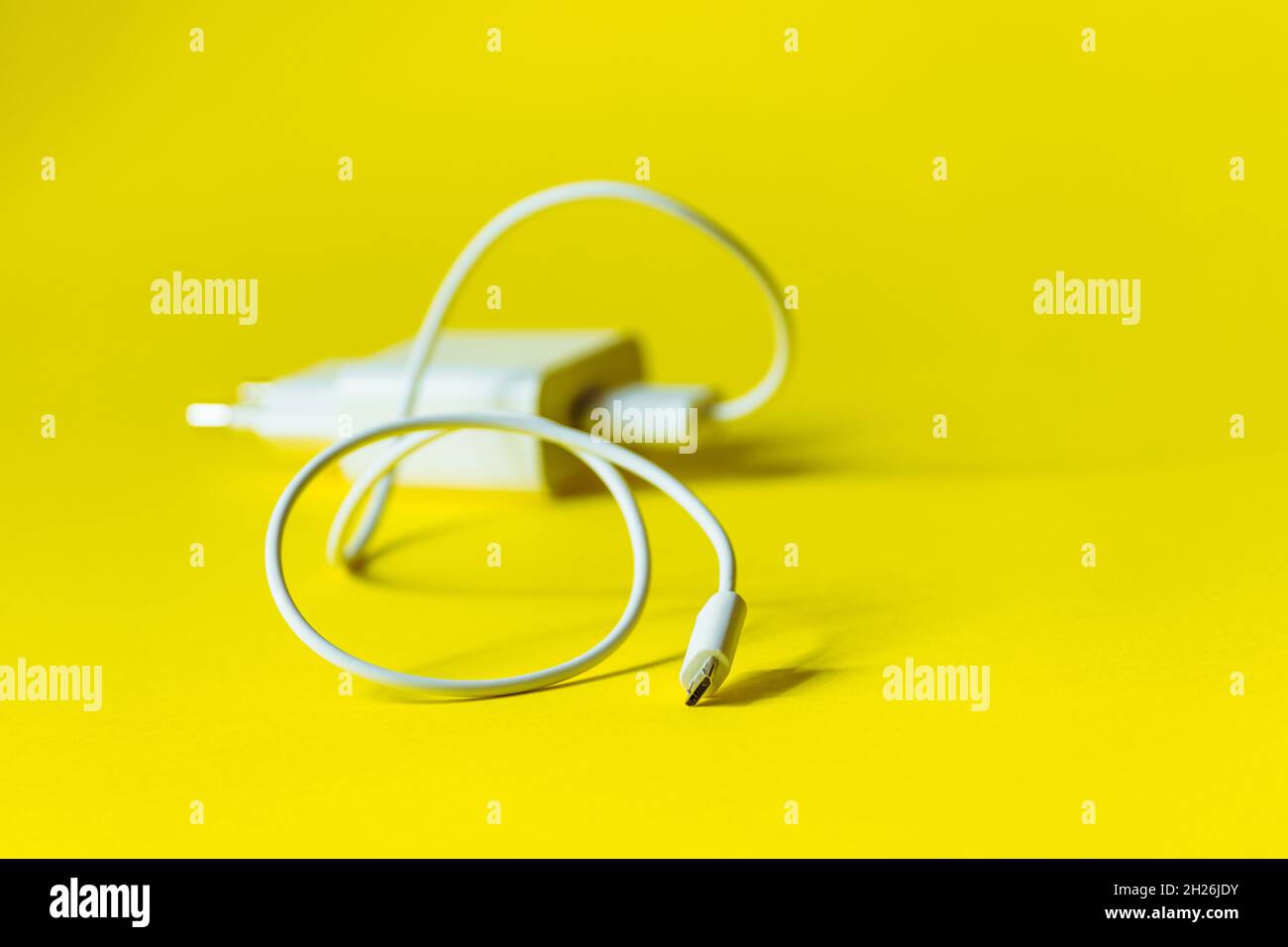 White charger with micro usb on a bright yellow background.  Stock Photo