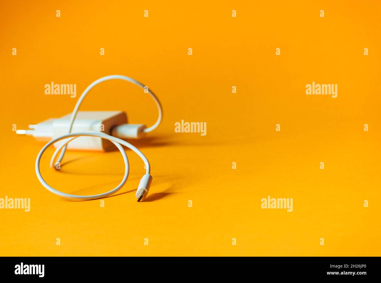 White charger with micro usb on a bright yellow background. Stock Photo