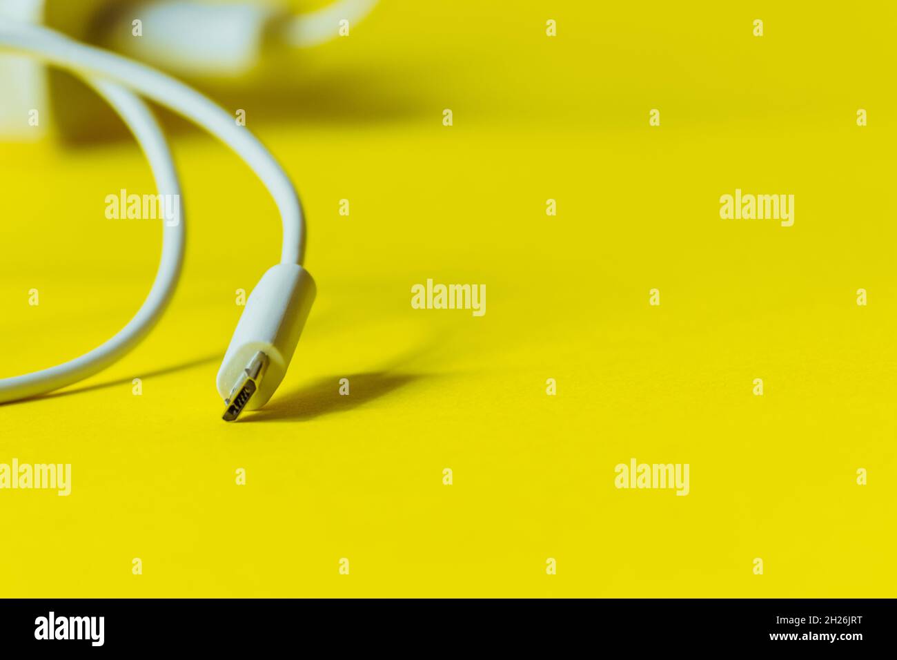 White cable with micro usb plug on a yellow background.  Stock Photo